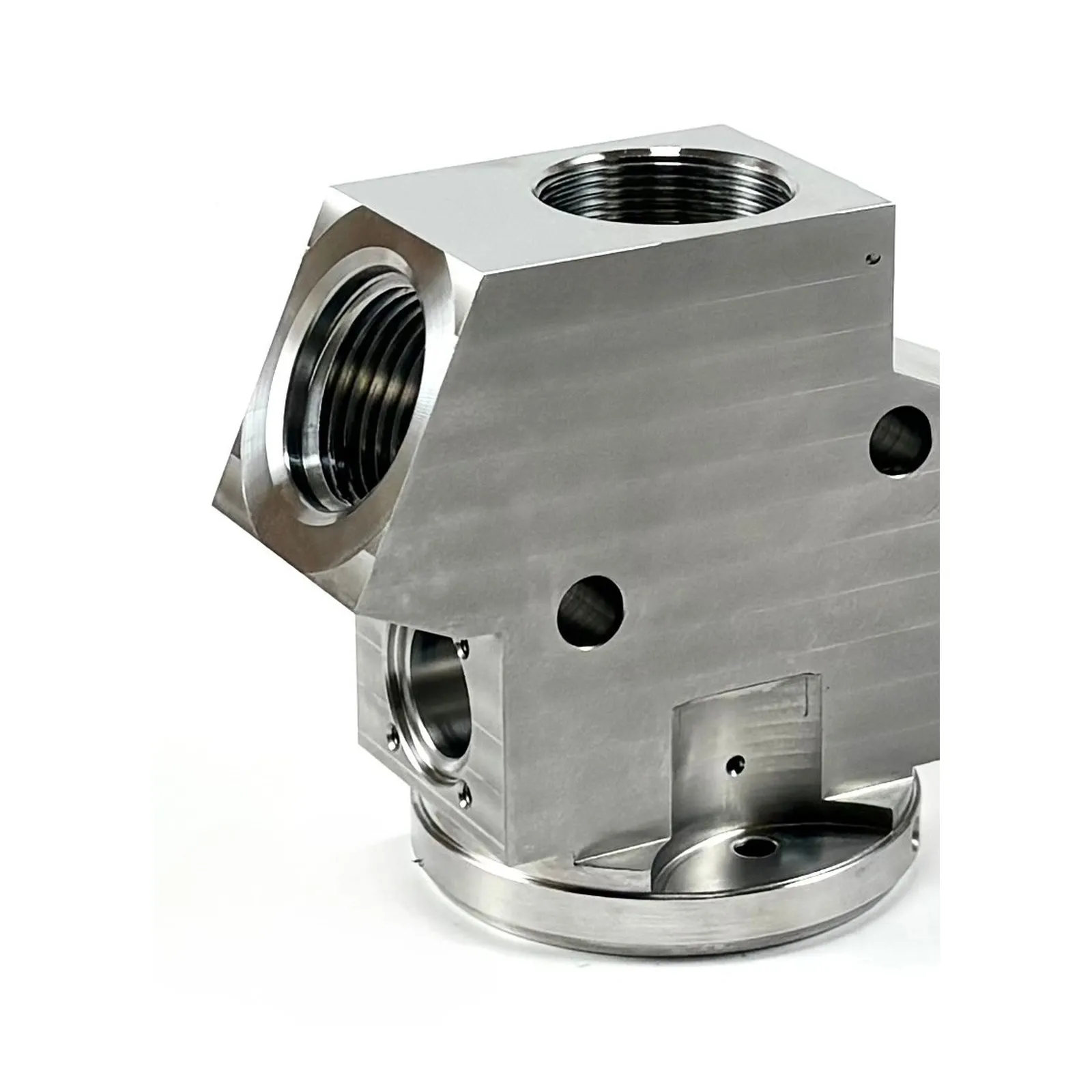 A multi-feature milled aluminum valve body with threaded ports and a turned circular base flange