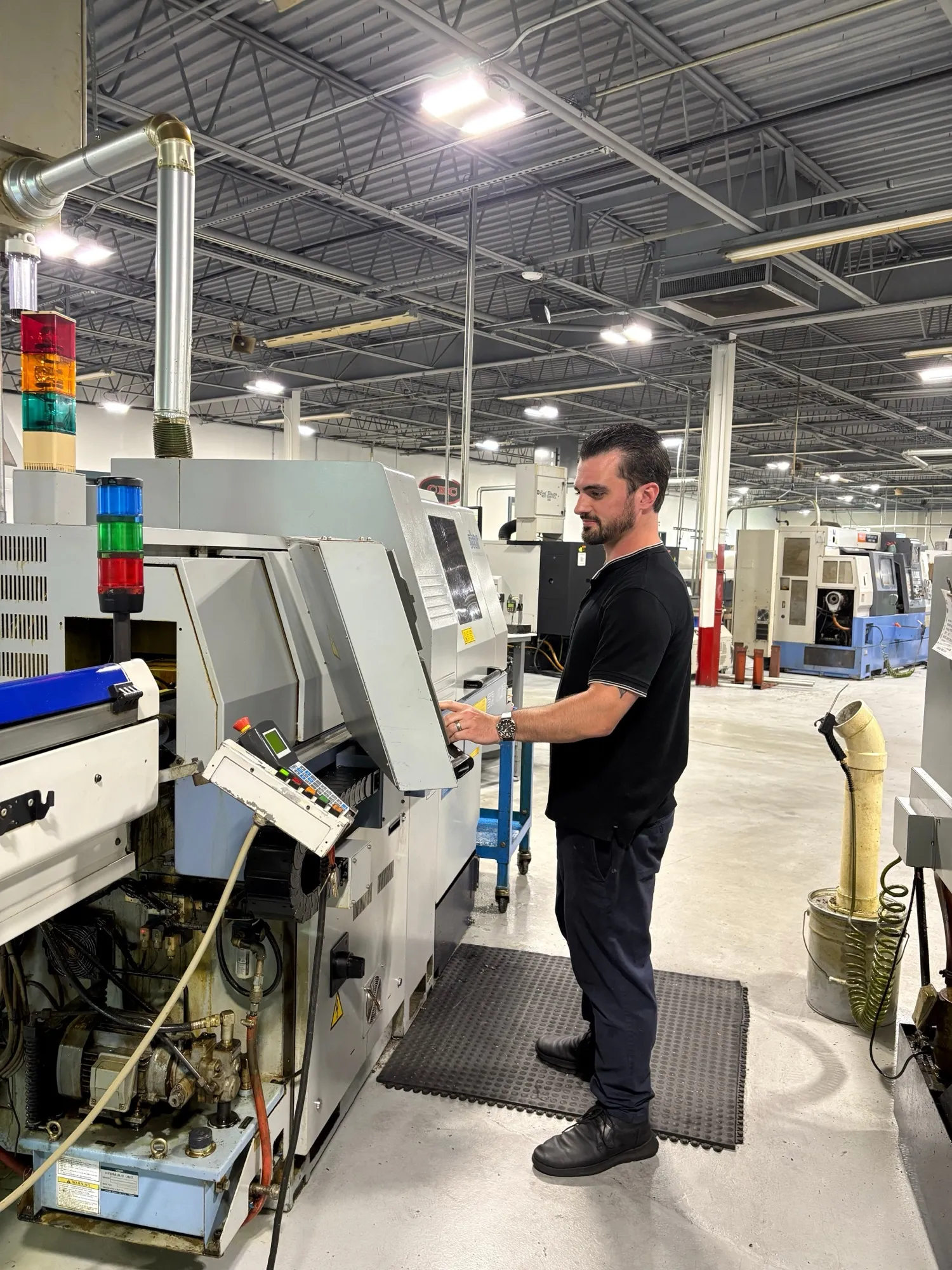 A CNC Manufacturing machinist operating a CNC turning center on the production floor