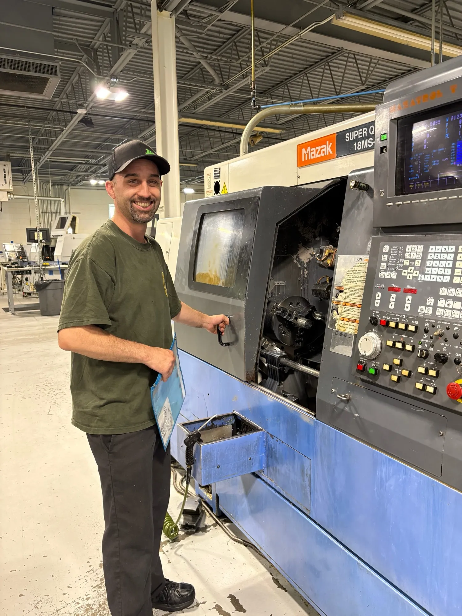 A CNC Manufacturing machinist at a Mazak SQT-18MSY CNC lathe on the production floor